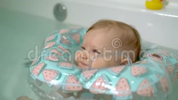 小婴儿在浴缸里游泳脖子上围着一个充气圈视频的预览图
