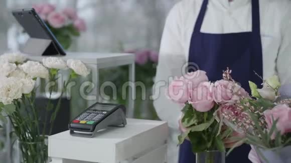 女性买家在一家现代花店购买漂亮的花束使用智能手机进行非接触支付视频的预览图