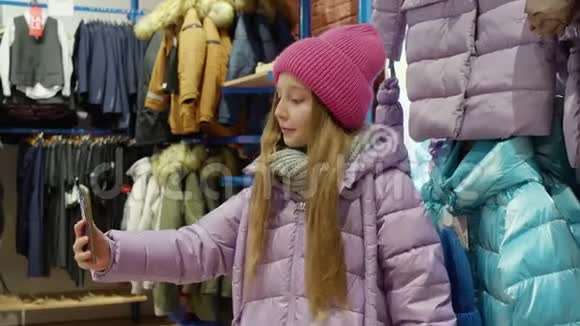 博客女孩拍摄在线视频到手机新衣服在时尚精品店年轻少女摆姿势视频的预览图