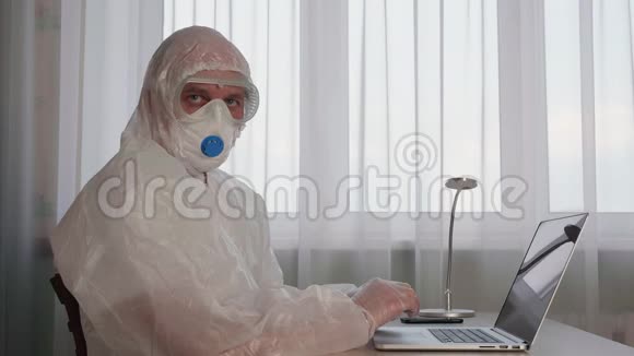 防疫检疫时穿着防护服装的办公室人员在手提电脑上工作穿白色防护服的男人视频的预览图