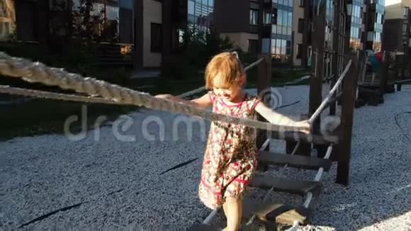 一个小女孩走在操场上的绳梯和绳桥上慢动作视频的预览图