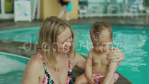 年轻的母亲和她的孩子们在游泳池里小女孩和她哥哥在游泳池里和妈妈玩得很开心视频的预览图