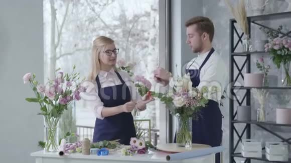 花艺年轻成功的专业花商收集美丽的鲜花花束给予五个微笑和外观视频的预览图