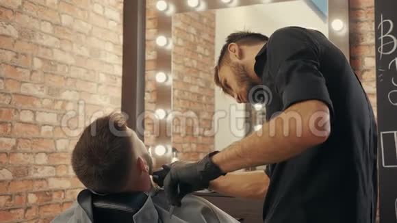 理发师用电动剃须刀刮胡子以时髦的人后景理发师带电机长胡须的人视频的预览图
