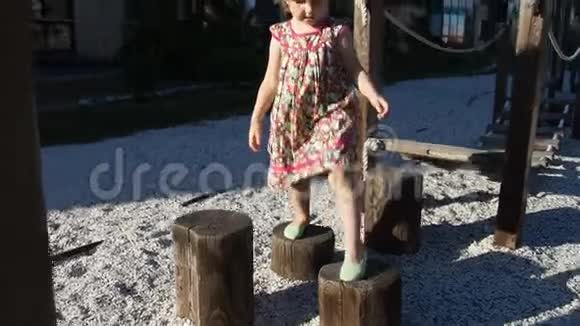 一个可爱的小女孩在电线杆和其他景点的游乐场散步慢动作视频的预览图