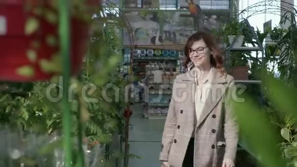 女人在花园里检查开花的植物女人带着眼镜用视觉购买盆栽的装饰植物视频的预览图