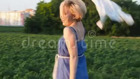 一个年轻的女人在种植园上欢快地跳跃她挥动她的手头发发展起来慢动作视频的预览图