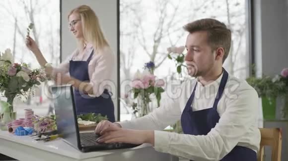 在线服务现代年轻的专家在花店接受在线购买专业的花艺师制作花束视频的预览图