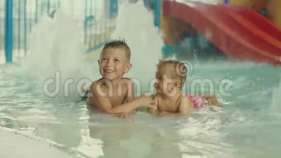 小男孩和小女孩在游泳池里玩得很开心哥哥和他妹妹在游泳池里玩视频的预览图