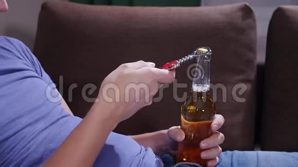 坐在沙发上的男人打开一瓶啤酒视频的预览图