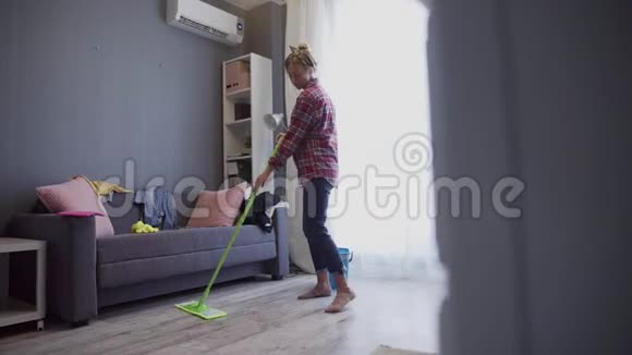 快乐的年轻女人可爱的家庭主妇用拖把洗地板在家跳舞视频的预览图