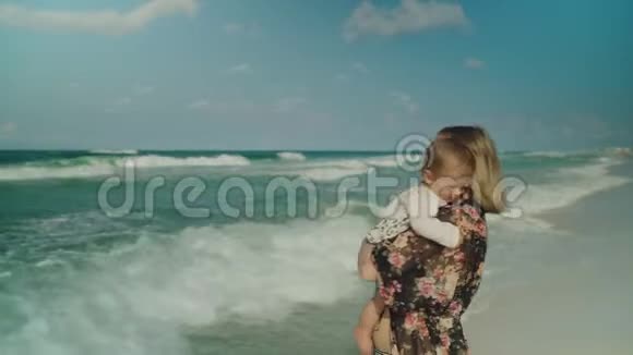 快乐的年轻母亲和她的女婴在巴拿马城海滩玩得很开心美国背景上的天空和海浪视频的预览图