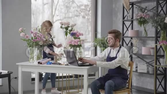 花店专业花店女士和男士从网上订购鲜花坐在桌边送花视频的预览图