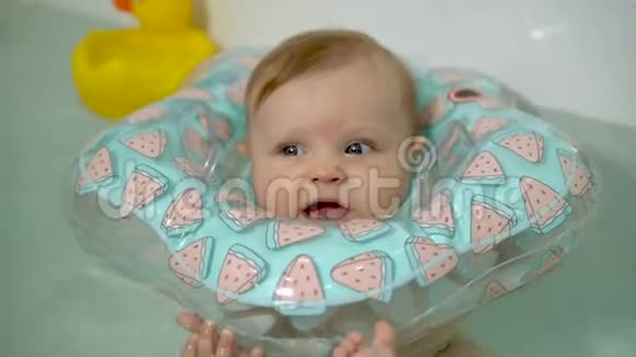 小婴儿在浴缸里游泳脖子上围着一个充气圈视频的预览图