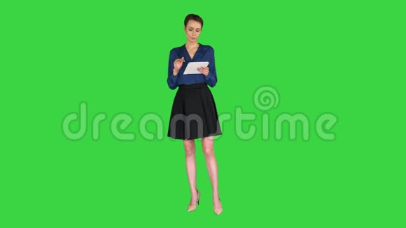 一位留着短发的女士穿着正装手里拿着一块平板电脑在绿色屏幕上对着摄像机讲话视频的预览图