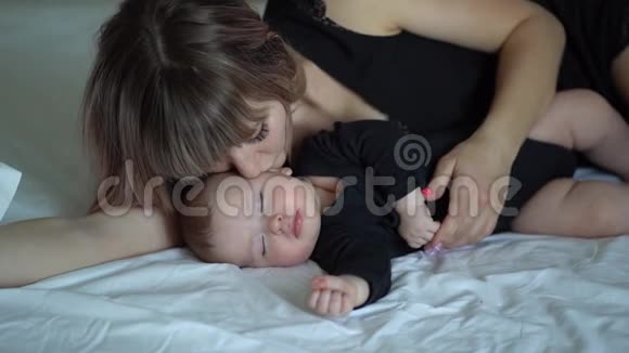 穿黑衣服的妈妈和宝宝躺在床上视频的预览图