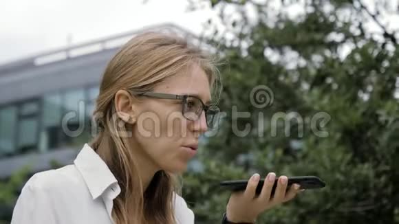 戴眼镜的妇女在户外使用智能手机语音识别功能视频的预览图