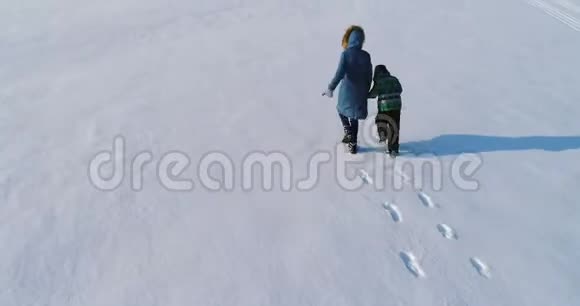 家人一起散步和玩耍冬天母子俩手牵手地在雪地里奔跑后面视频的预览图