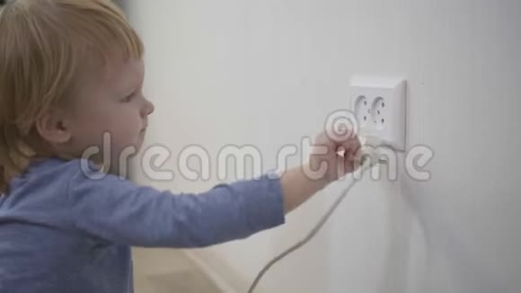 在家里处境危险的孩子小男孩试图把电源插头插入插座特写视频的预览图