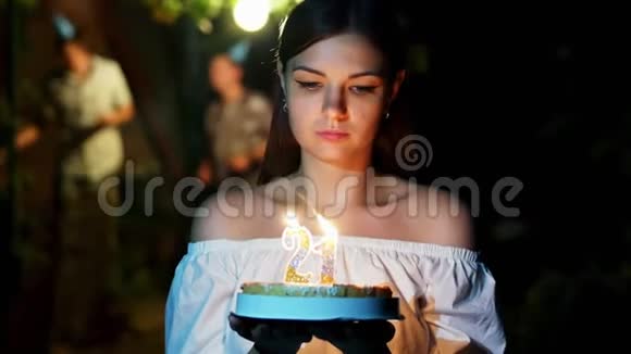 美女拿着生日蛋糕和蜡烛站着许愿朋友们在后台跳舞视频的预览图