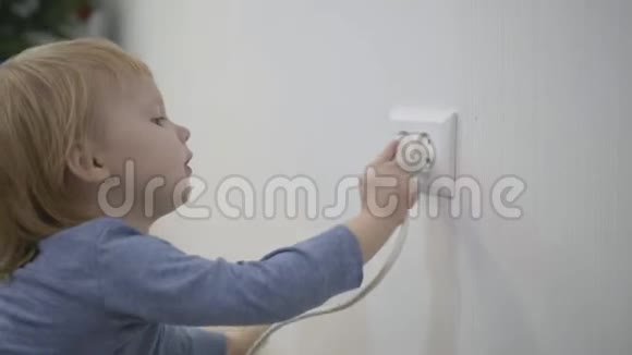 小孩试图将电源插头插入插座特写镜头一个小男孩在家里危险地玩耍视频的预览图
