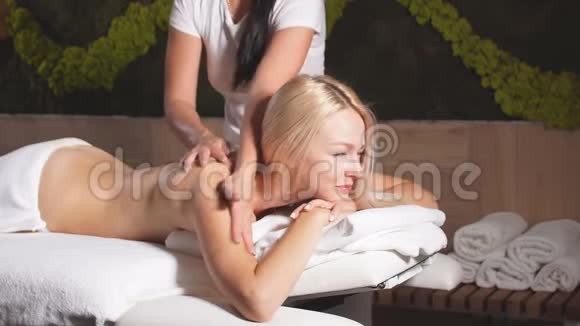 专业按摩治疗师的双手在金发美女的背上按摩视频的预览图