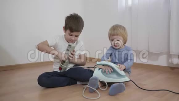 家里的危险情况孩子们坐在地板上玩电手里拿着电源插座腿上拿着法兰盘视频的预览图