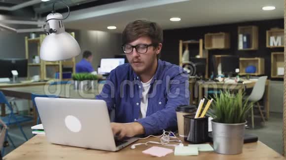 有创意的人戴着眼镜在办公室工作时喝着咖啡视频的预览图