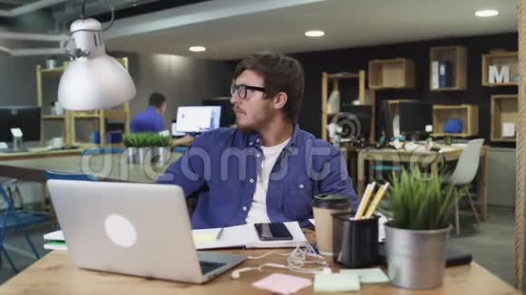年轻的成功商人坐在现代办公室里看镜头的肖像视频的预览图