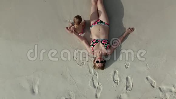 鸟瞰躺在沙滩上的妇女和她的女婴视频的预览图