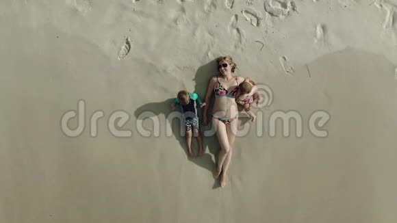 海滩上躺着的女人和孩子的鸟瞰图视频的预览图