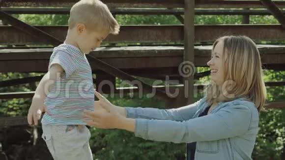 漂亮的年轻妈妈和活泼可爱的金发男孩在玩玩得很开心女人爱她的儿子美丽的年轻妈妈视频的预览图