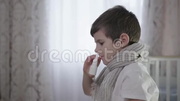 流感期间戴暖和围巾的生病的孩子鼻塞在家里坐在床上用一滴药视频的预览图
