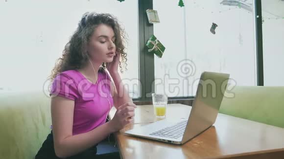 微笑的女人在咖啡馆里用笔记本电脑视频的预览图