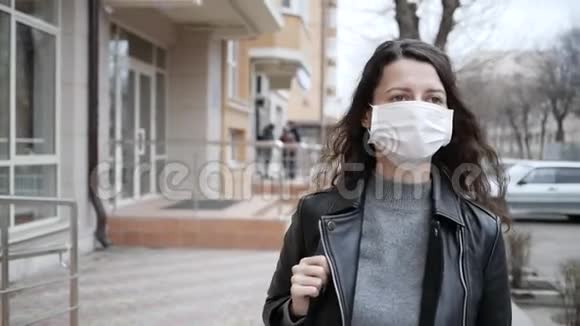 戴着医用防护面罩的年轻女子在城里四处走动慢动作冠状病毒视频的预览图