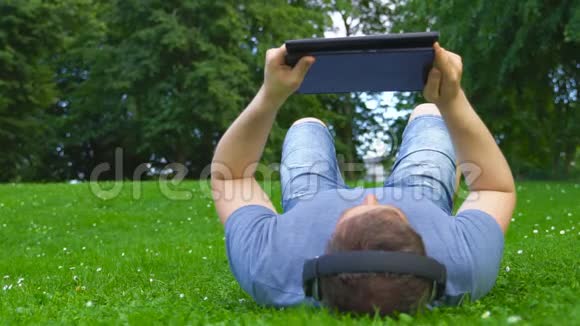 躺在草地上的人拿着平板电脑视频的预览图
