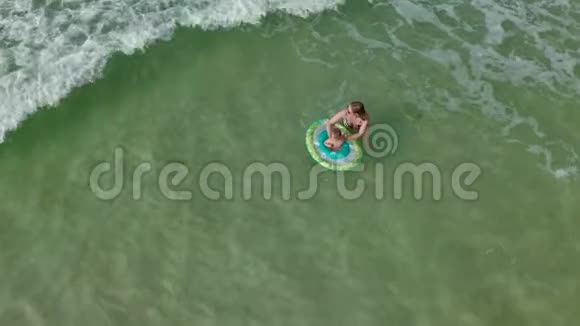 年轻的女人和一个小女孩一起在海里游泳从上面看有游泳圈的女婴视频的预览图