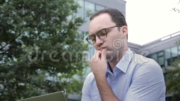 戴着眼镜的年轻男性新手厌倦了在笔记本电脑上工作视频的预览图