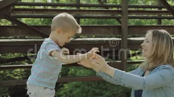 漂亮的年轻妈妈和活泼可爱的金发男孩在玩玩得很开心女人爱她的儿子漂亮的年轻妈妈视频的预览图