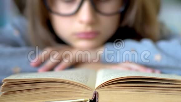 一个戴着大黑眼镜的女孩正在看书前景是一本书关闭视野视频的预览图