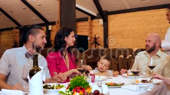 一家人在餐馆吃饭桌上有丰盛的食物和酒精饮料一群朋友和亲戚围坐在桌子旁视频的预览图