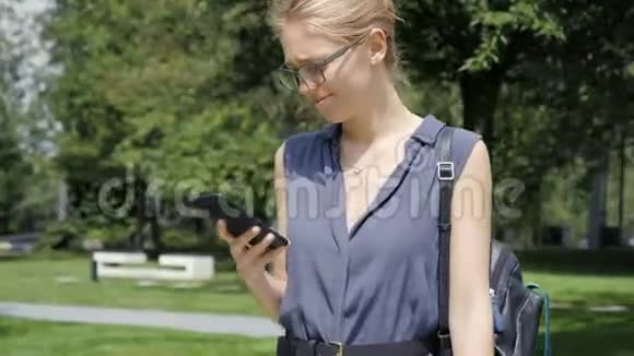 戴眼镜的年轻美女在公园里打电话视频的预览图