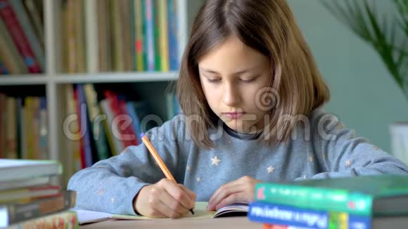 一个女孩坐在桌子旁在笔记本上写字悲伤疲惫的样子关闭视野视频的预览图