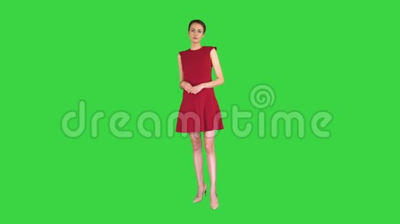 兴奋的美丽年轻女子穿着红色连衣裙在绿色屏幕上与相机交谈Chroma键视频的预览图