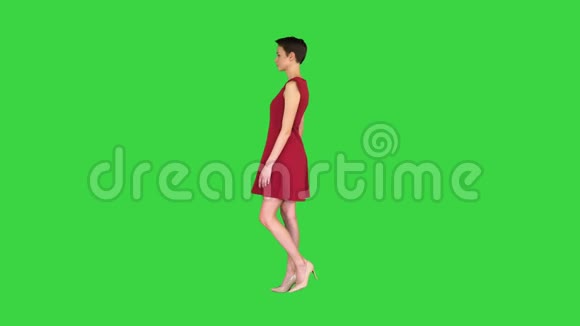 女孩试着穿红色连衣裙转过身来就像在绿色屏幕上照镜子铬钥匙视频的预览图