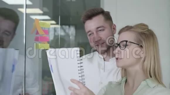 商界人士男人和女人用玻璃白板上的黏糊糊的音符头脑风暴小组的组长女人和视频的预览图