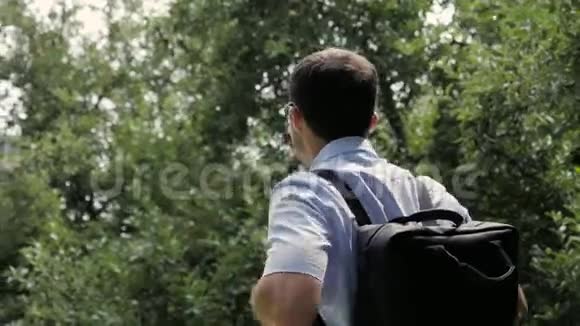 英俊的年轻人戴着眼镜和休闲服带着黑色背包走路视频的预览图
