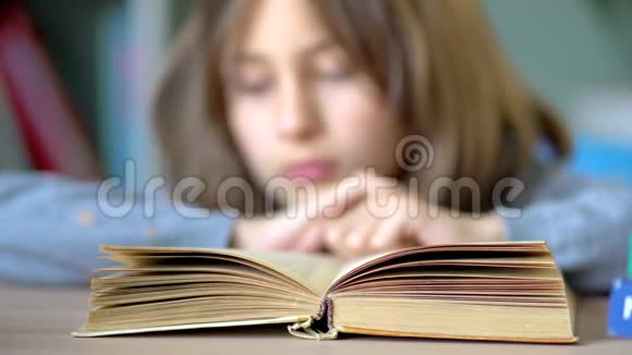 最喜欢的爱好是读书桌子上有一本打开的书一个年轻的女学生读起来很感兴趣关闭视野视频的预览图