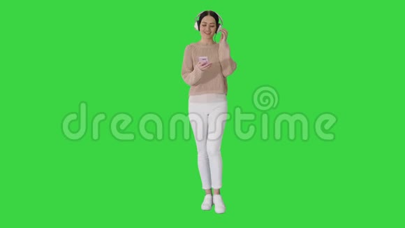 美女一边散步一边在绿色屏幕上听音乐Chroma键视频的预览图