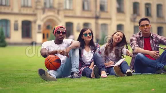 快乐的学生一起坐在大学附近的草地上视频的预览图